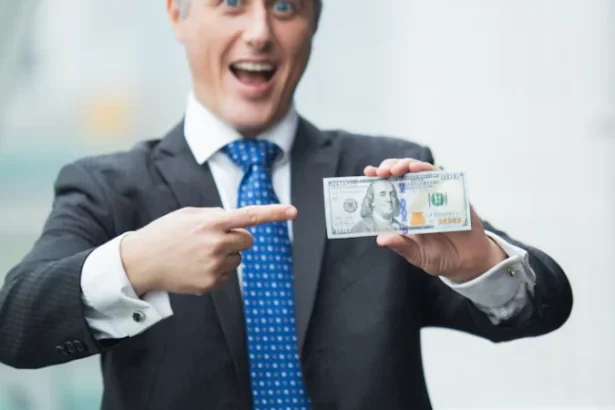 Man in a suit excitedly points at a hundred-dollar bill, emphasizing financial success or lending.