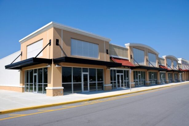 Row of commercial storefronts with large glass windows and awnings under a clear blue sky.