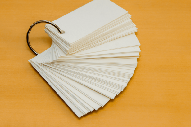 A stack of blank flashcards fanned out on a wooden surface, held together by a metal ring.
